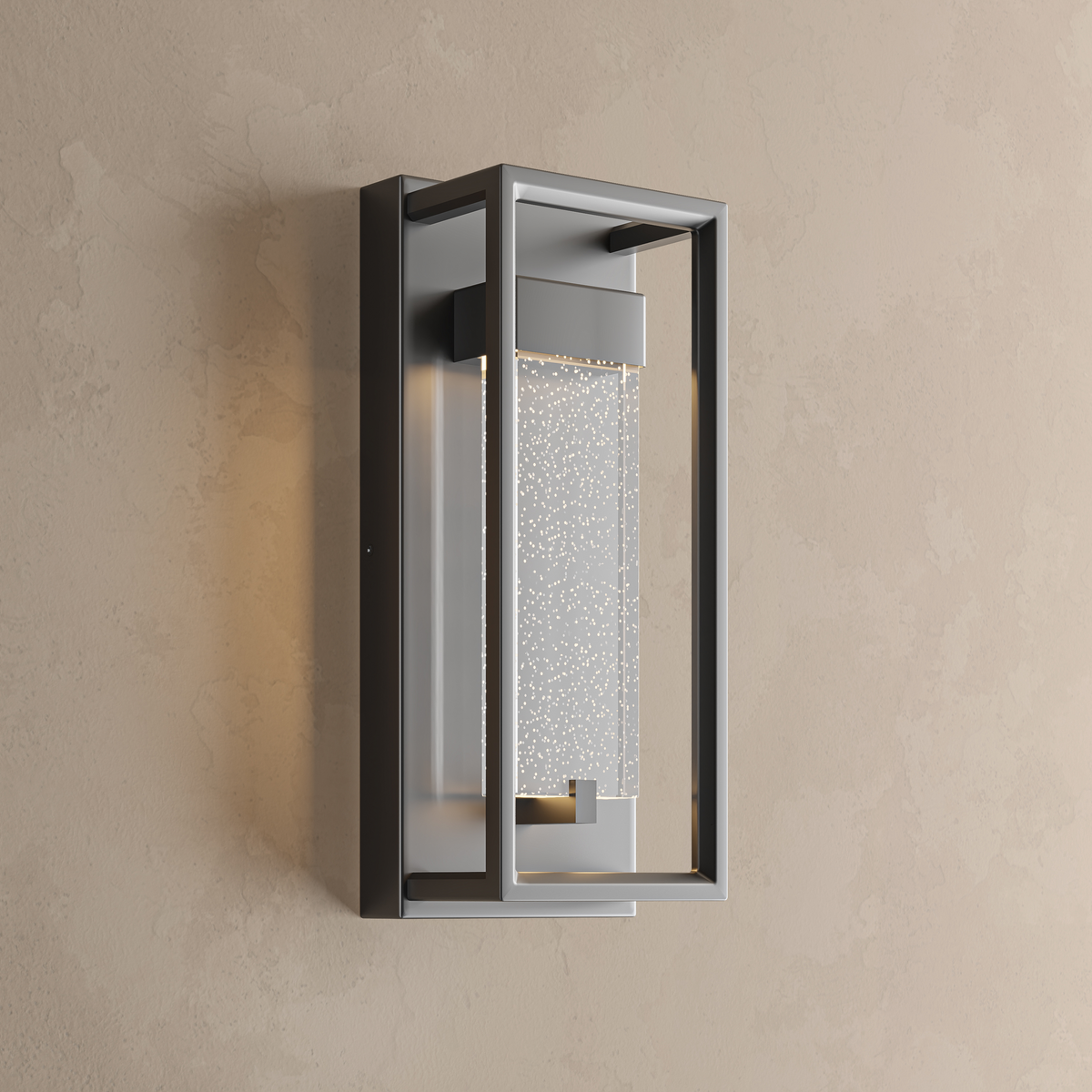 Applique extérieure noire à cadre ouvert allumée, cœur en verre à bulles effet étoilé, sur un mur beige