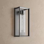 Applique murale extérieure noire, cadre rectangulaire ouvert en inox et cylindre de verre texturé avec ampoule LED T10, sur un mur enduit beige