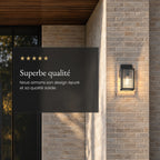 Applique lanterne noire allumée sur un mur en briques claires, avis client 5 étoiles : « Superbe qualité »