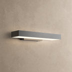 Applique murale extérieure horizontale noire allumée, lumière blanc chaud diffusée vers le bas, sur un mur enduit beige