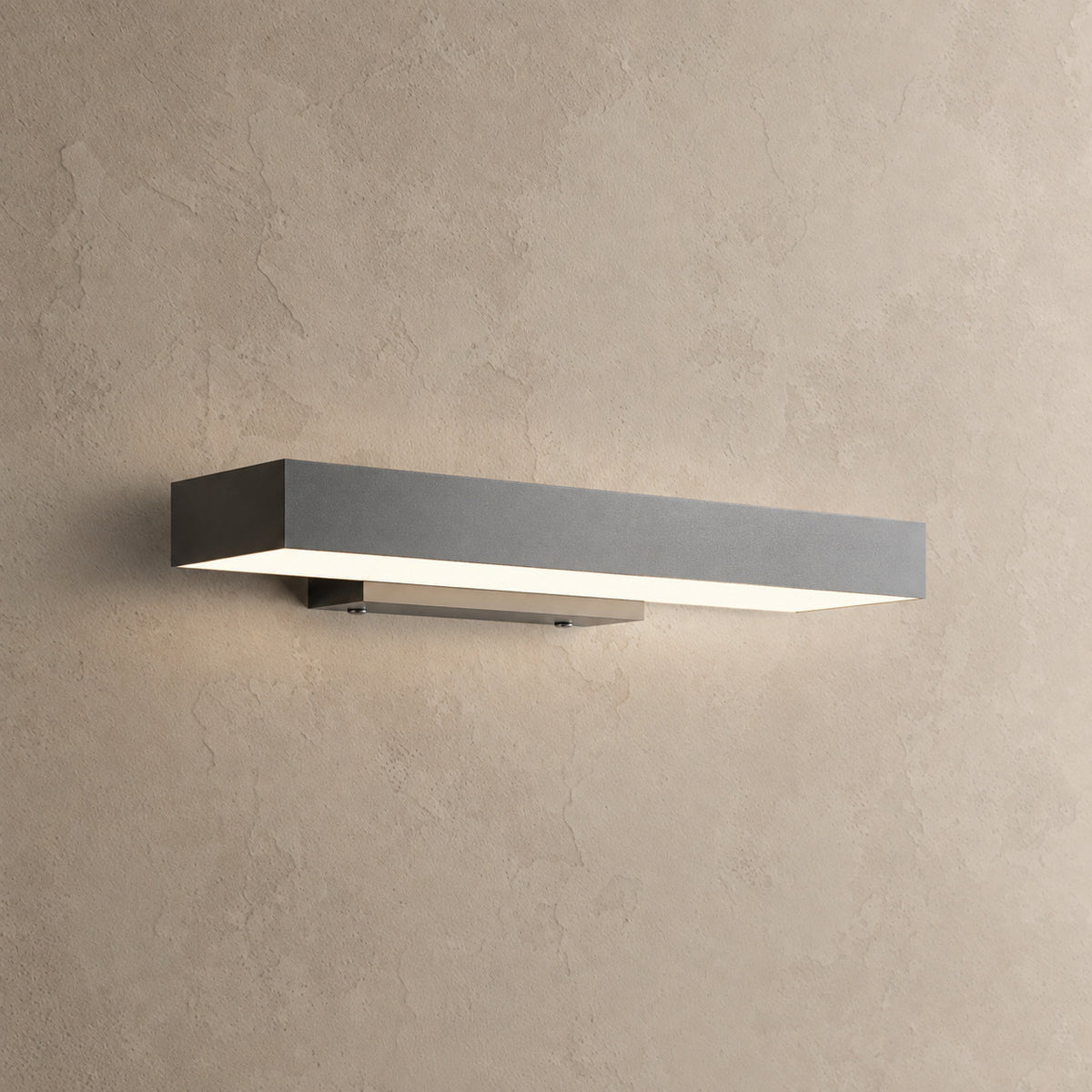 Applique murale extérieure horizontale noire allumée, lumière blanc chaud diffusée vers le bas, sur un mur enduit beige