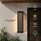Applique extérieure noire à lames sur un mur enduit sous la pluie : résiste aux intempéries et à la rouille, par soleil, neige, brouillard ou pluie