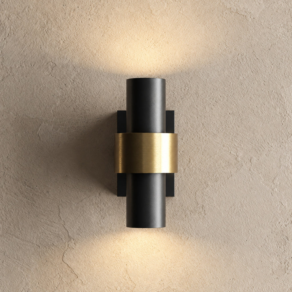 Applique extérieure cylindrique noire à bague dorée, allumée vers le haut et vers le bas sur un mur enduit beige