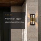 Applique extérieure noire et dorée allumée sur un mur en briques blanches, avis client 5 étoiles