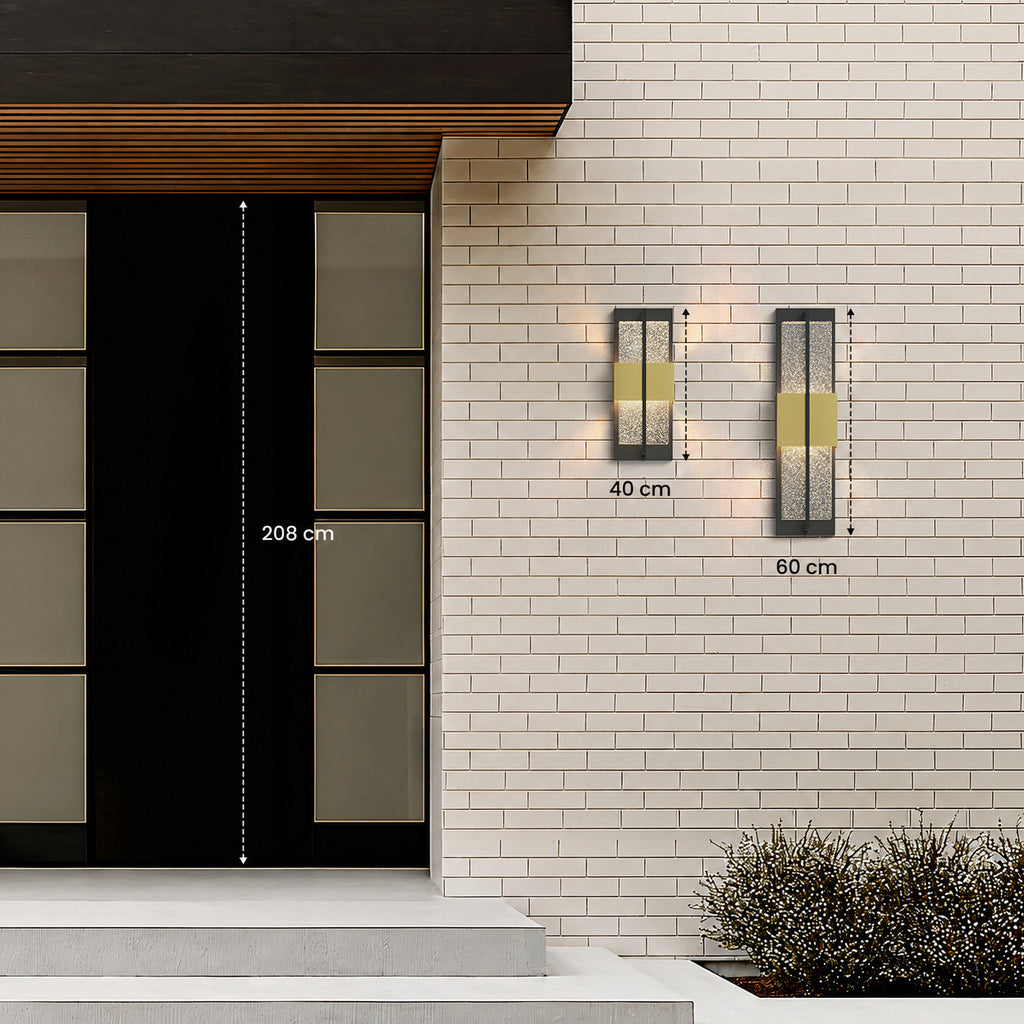 Les deux tailles de l’applique extérieure noire et dorée, 40 et 60 cm de haut, à côté d’une porte d’entrée de 208 cm