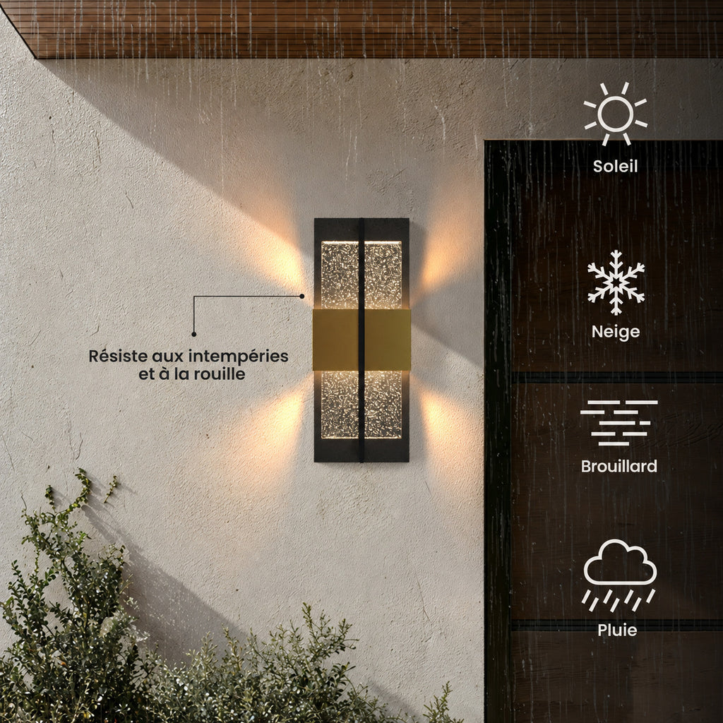 Applique extérieure noire et dorée allumée sur un mur enduit : résiste aux intempéries et à la rouille, par soleil, neige, brouillard ou pluie