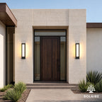 Paire d’appliques extérieures solaires noires allumées encadrant une porte d’entrée contemporaine