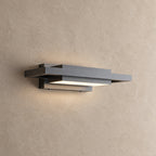 Applique extérieure noire à plans décalés allumée, vue de trois quarts sur un mur beige