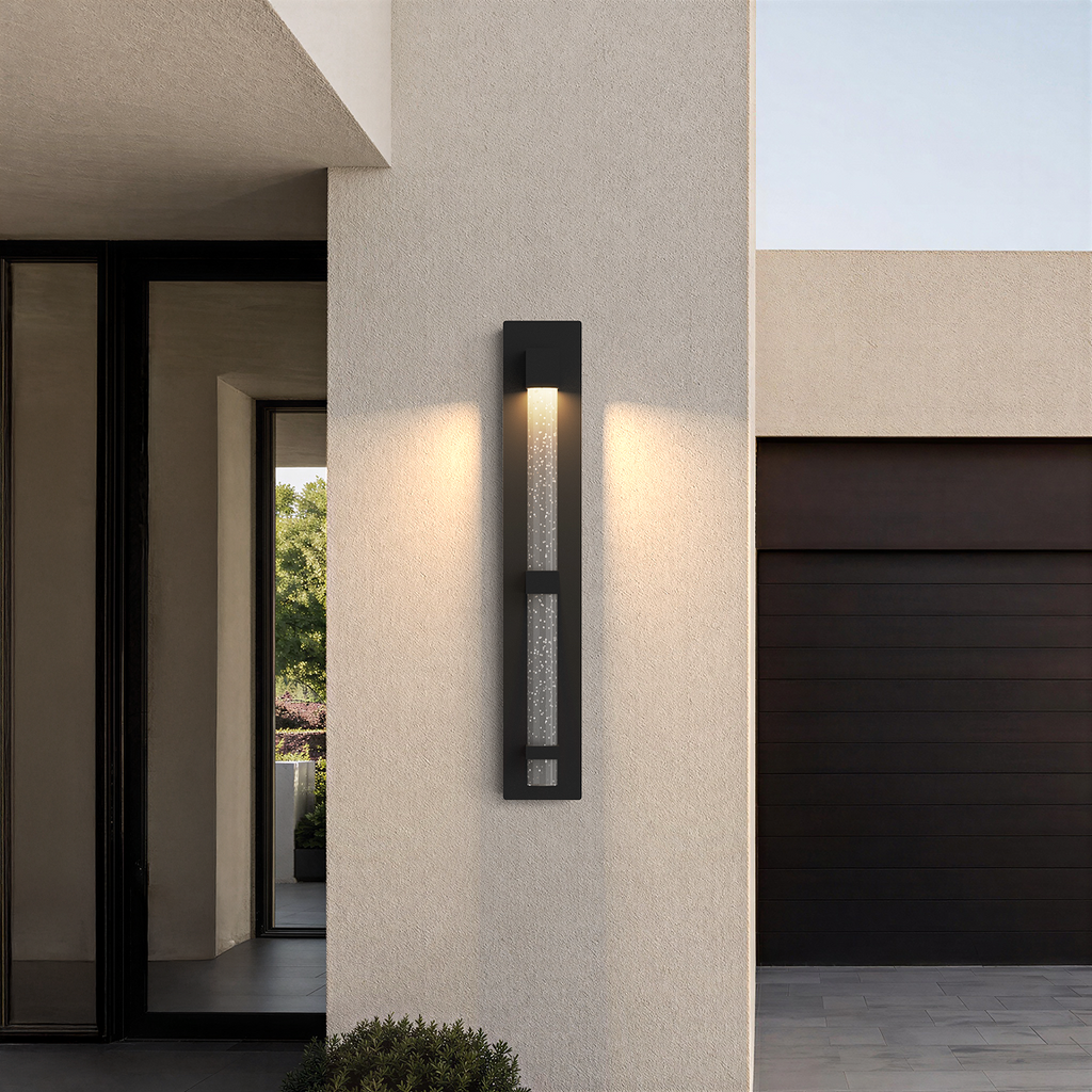 Applique extérieure noire taille Grand, 73 cm, allumée sur la façade d’une maison moderne, près de l’entrée et du garage