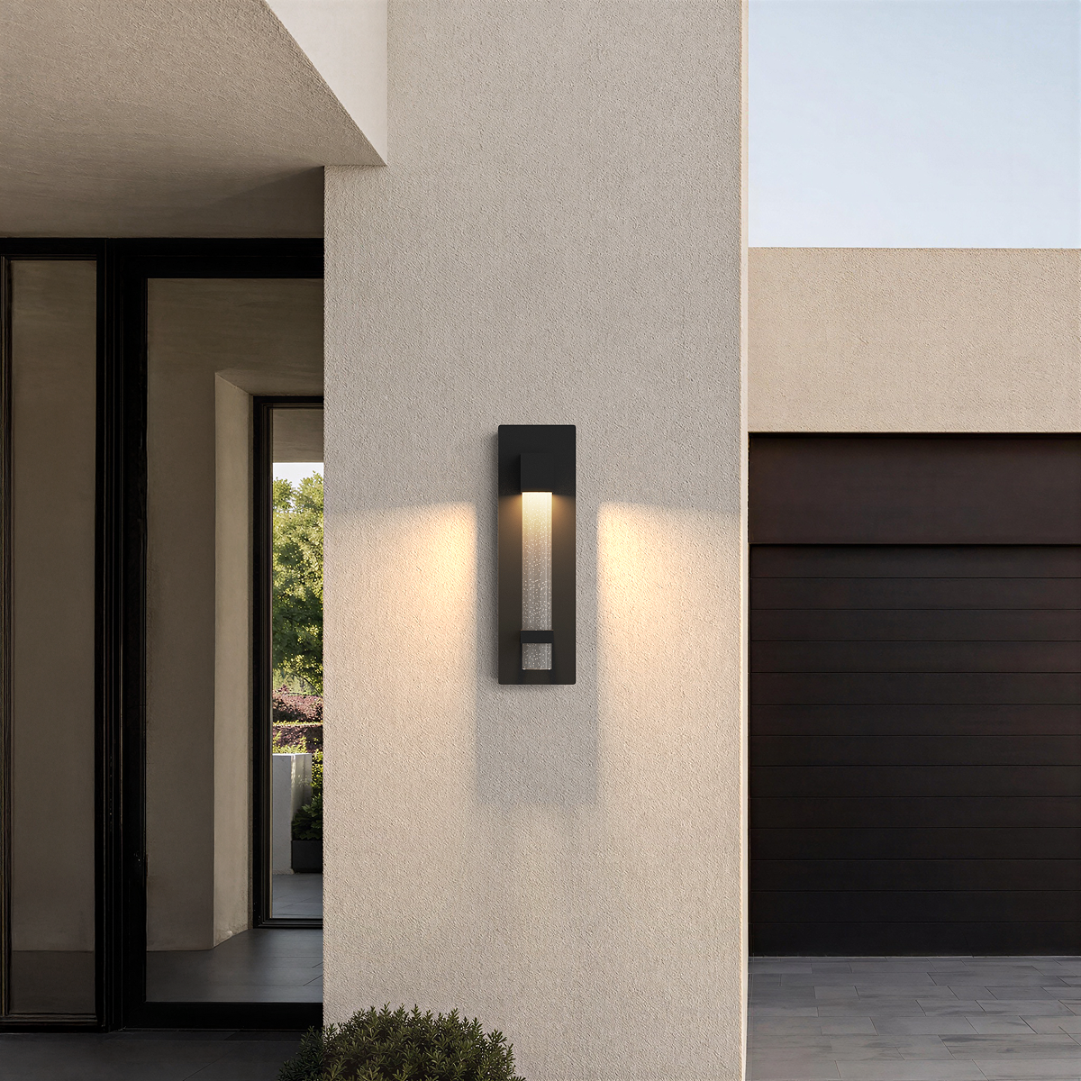 Applique extérieure noire taille Moyen, 40 cm, allumée sur la façade d’une maison moderne, près de l’entrée et du garage