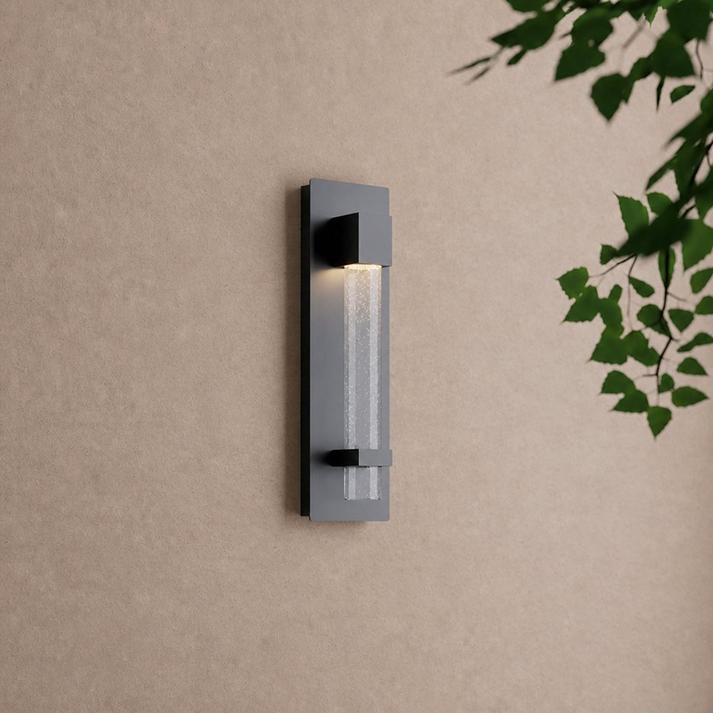 Applique extérieure verticale noire allumée sur un mur enduit, feuillage au premier plan