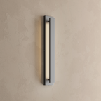 Applique extérieure LED lame verticale noire allumée, fine bande de lumière blanc chaud sur un mur enduit beige