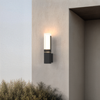 Applique extérieure noire, modèle simple allumé en partie haute sur une façade enduite