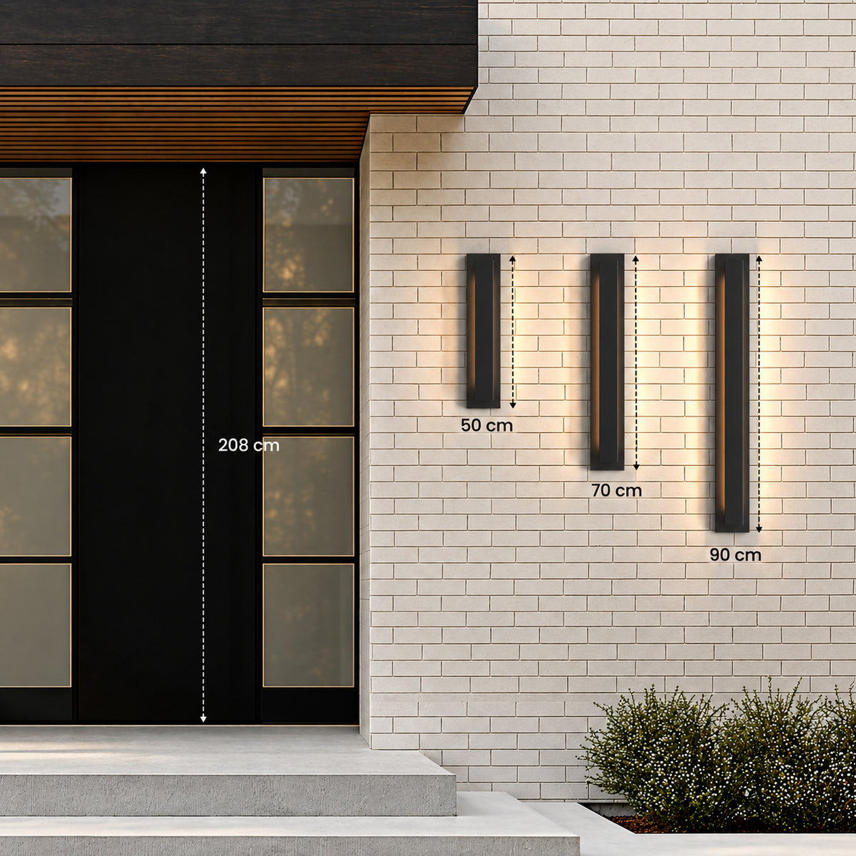 Trois appliques extérieures LED verticales noires sur un mur en brique claire : 50 cm, 70 cm et 90 cm, à côté d’une porte de 208 cm